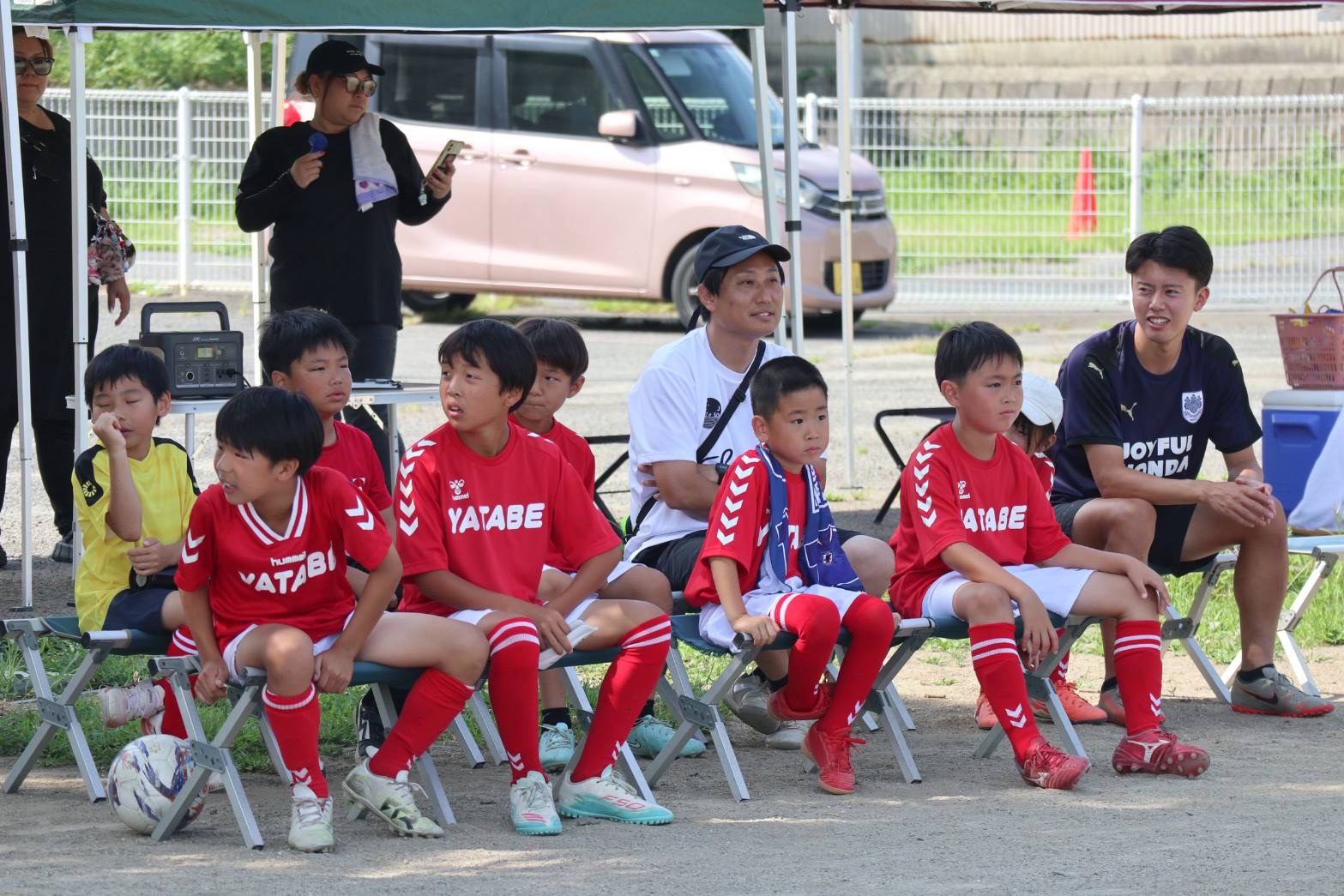 子どもたちと同じベンチで試合を見守るコーチ