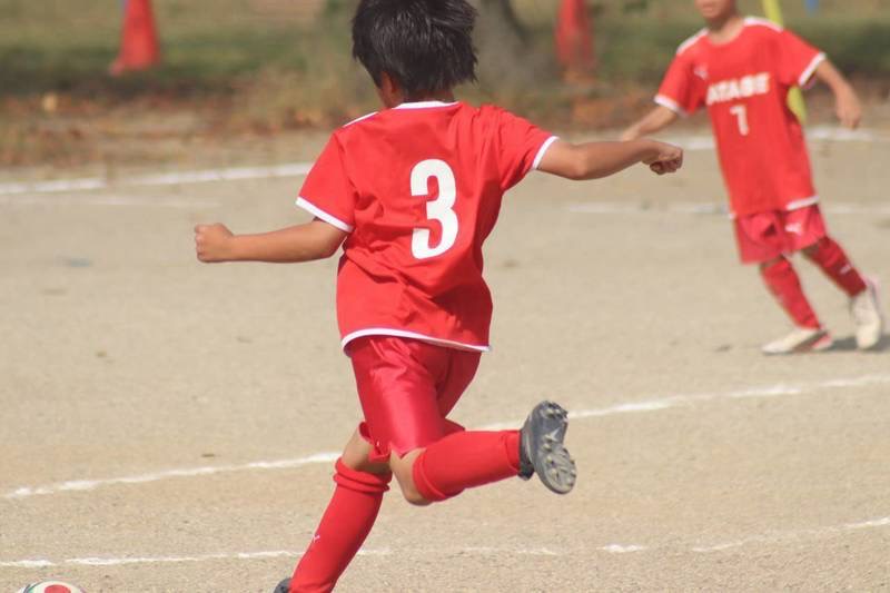 赤いユニフォームでボールを蹴る谷田部FCの選手
